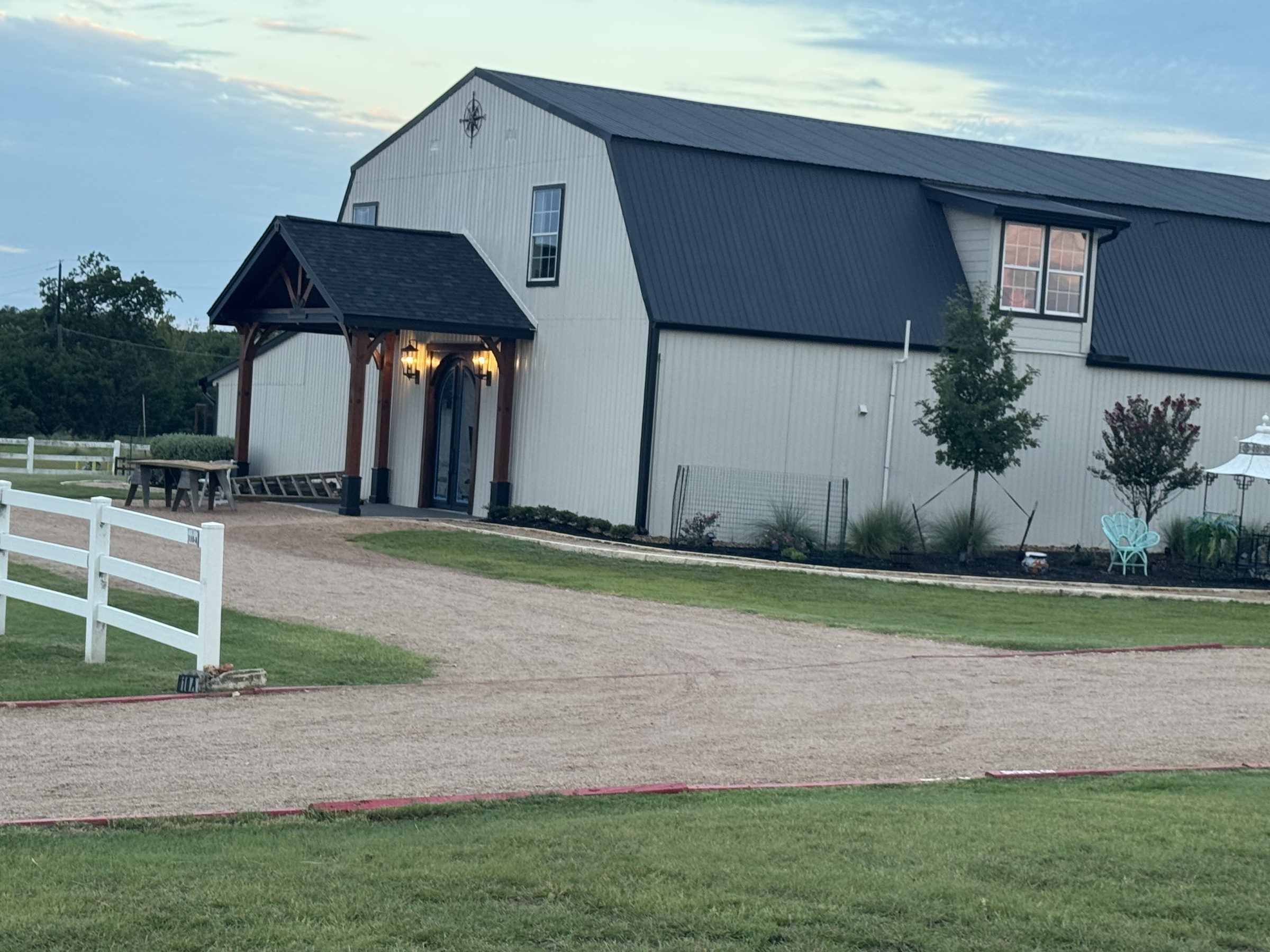 The barndominium exterior with covered portico entrance - daytime, ready for arriving guests.
