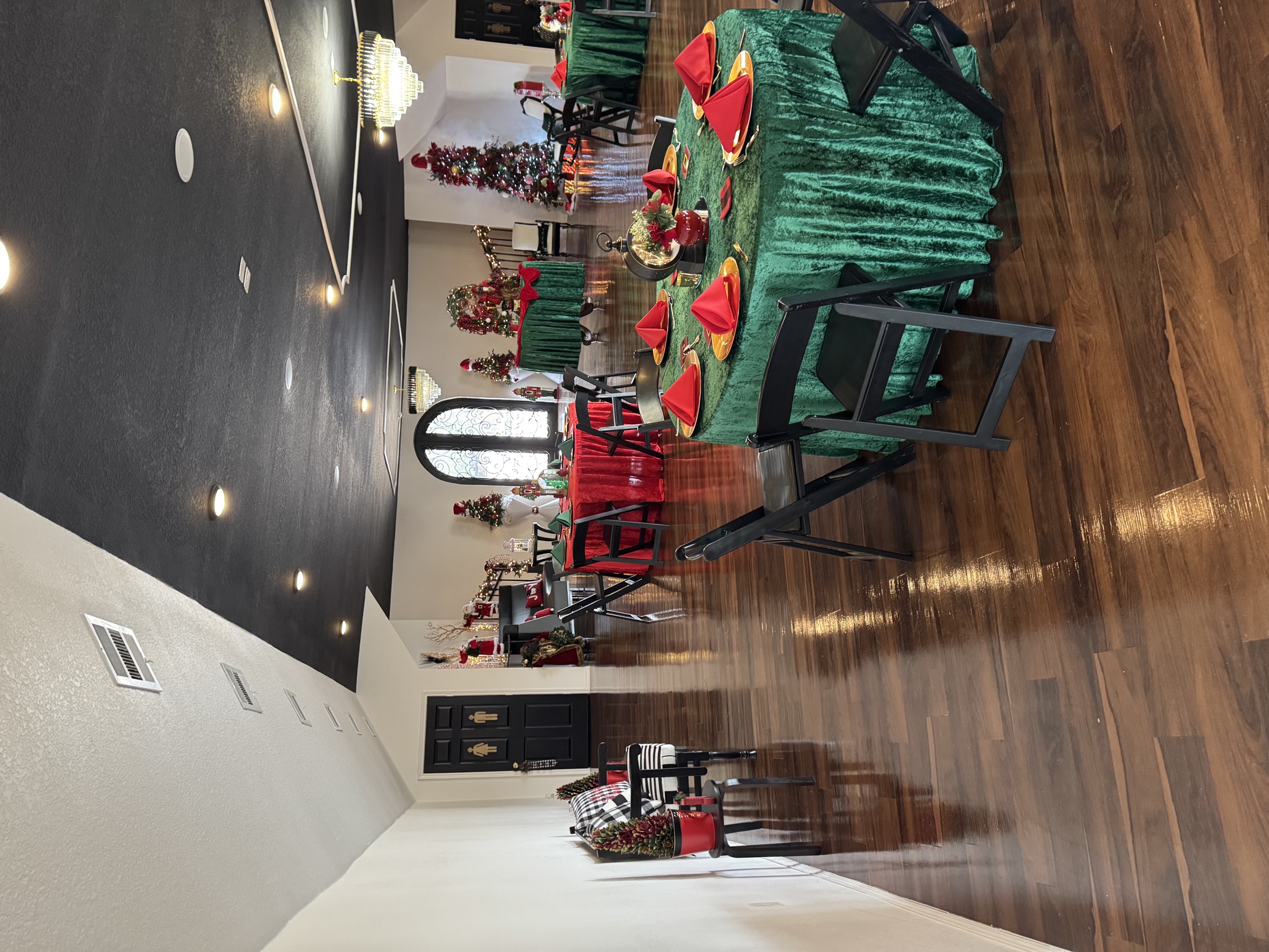 Christmas event setup at the venue - green velvet tables, red napkins, Christmas trees, and festive accents.